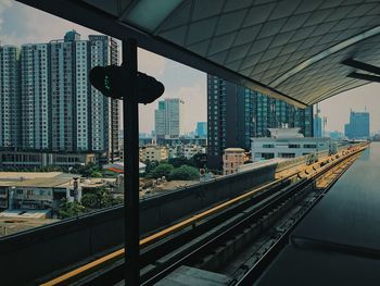 Railroad tracks by buildings in city against sky