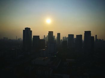 Modern buildings in city against clear sky during sunset