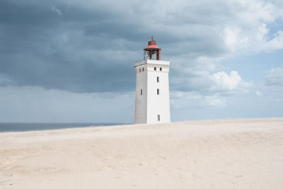 Lighthouse by sea against sky