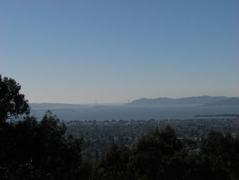 High angle view of sea and cityscape against clear blue sky