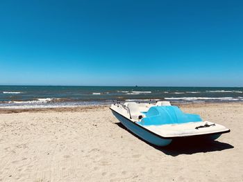 Boat on beach against clear blue sky