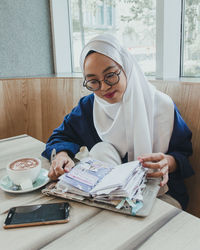 Woman looking at book by coffee in restaurant