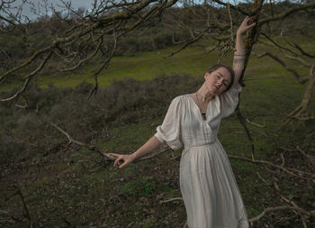 Woman standing by tree trunk