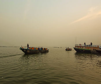 Boat sailing in sea against sky during sunset