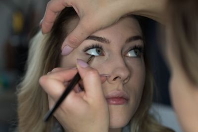 Close-up of beautician applying eyeliner to young woman