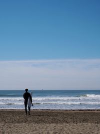 Man walking on beach against sky