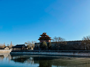 View of building by lake against blue sky