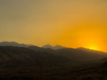 Scenic view of silhouette mountains against orange sky