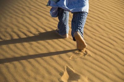 Low section of person walking on sand