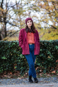 Portrait of smiling young woman standing against trees