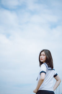 Portrait of a beautiful young woman standing against sky