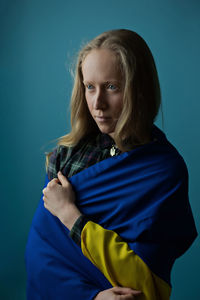 Portrait of young woman looking away against blue background