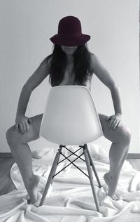 Naked woman sitting on chair at home