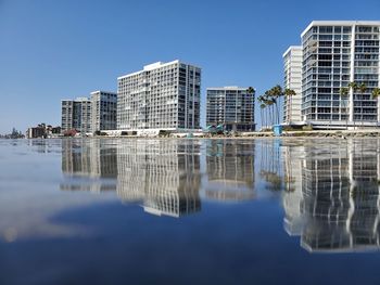 Reflection of buildings in lake against clear sky