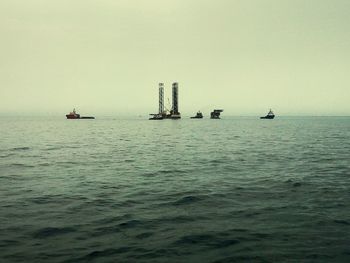 Boats sailing in sea against clear sky