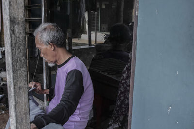 Side view of man looking away while sitting by glass