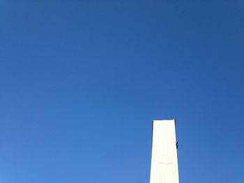 Low angle view of trees against clear blue sky