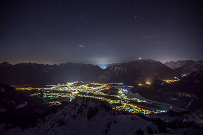 Aerial view of illuminated snowcapped mountains against sky at night