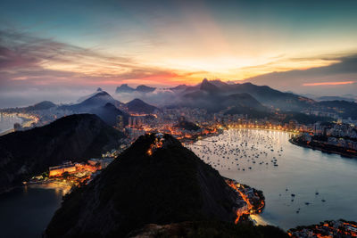 Aerial view of illuminated city against sky during sunset