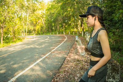 Woman listening music while standing on roadside