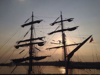 Sailboats moored in sea against sky during sunset