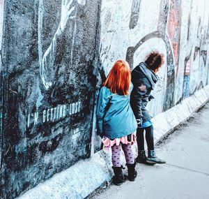 Rear view of women standing on wall