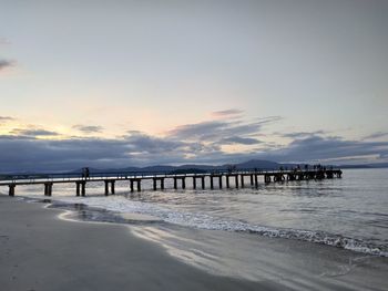 Pier over sea against sky during sunset