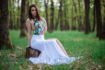 Young woman sitting on field in forest