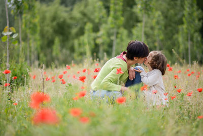 Side view of mother and daughter kissing in grassy field