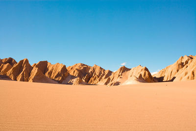 Scenic view of desert against clear blue sky