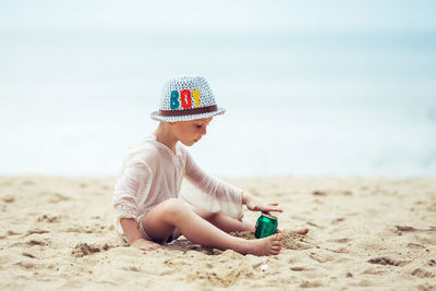 Side view of woman wearing hat standing at beach