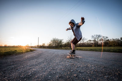 Man skateboarding on road against sky