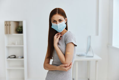 Portrait of woman wearing mask standing at hospital