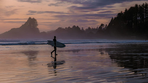 Silhouette man standing in lake during sunset