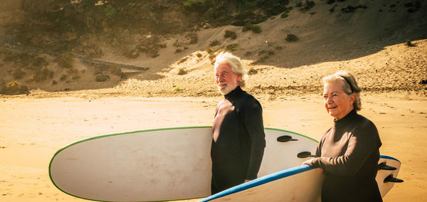 Senior couple holding surfboards at beach