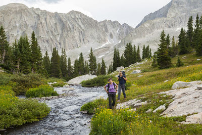 People on rocks against mountains