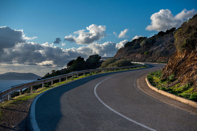 Empty road by mountain against sky