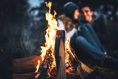 Young couple enjoying campfire in forest at dusk