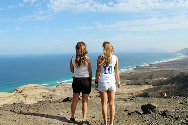 leisure activity, lifestyles, sea, real people, sky, togetherness, women, land, rear view, water, nature, scenics - nature, two people, beauty in nature, beach, standing, casual clothing, friendship, day, hair, outdoors, hairstyle, horizon over water, looking at view