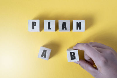 Close-up of hand holding yellow text on wall