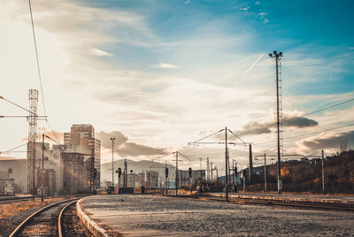 Railroad tracks by road against sky