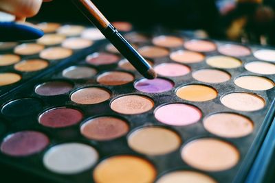 Close-up of make-up brush and pink face powder on purple table