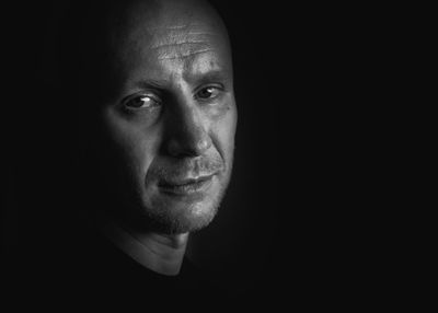 Close-up portrait of man against black background