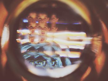 Portrait of woman photographing reflection in illuminated mirror