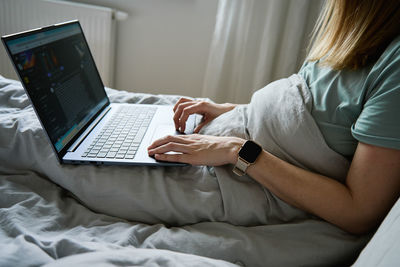 Midsection of woman using laptop at home