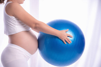 Midsection of woman with ball on blue table