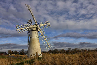 Traditional windmill on field against sky