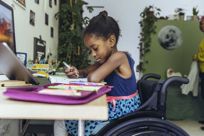 Disabled girl studying at desk in bedroom