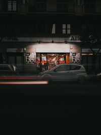 Car on street against illuminated buildings in city