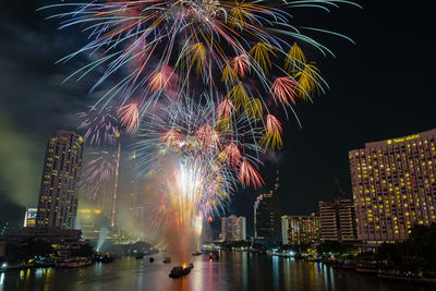 Firework display in city against sky at night